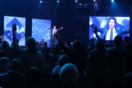 Attendees lift their hands in prayer during televangelist Joel Osteen's