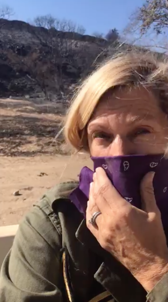 Actress Brenda Epperson standing in her yard pointing to the mountains that are completely scorched by the California campfire, November 2018.