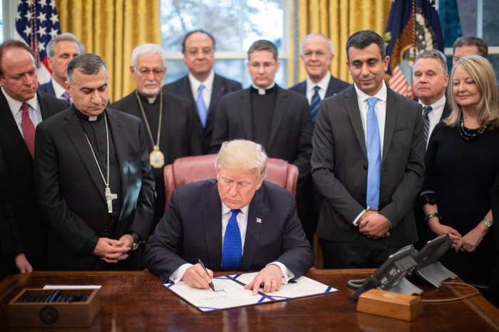  President Donald Trump is joined by legislators and Archbishop Bashar Warda of Erbil-Kurdistan, Iraq, left, as he signs H.R. 390-Iraq and Syria Genocide Relief and Accountability Act of 2018 Tuesday, Dec. 11, 2018 in the Oval Office of the White House. 