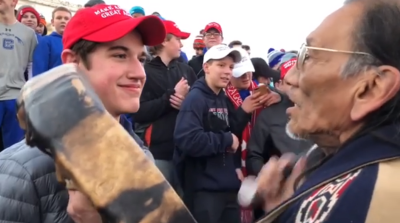 Nicholas Sandmann (L), a junior at Covington Catholic High School in Kentucky, smiles at Nathan Phillips (R), an Omaha elder and former United States Marine as he played a ceremonial drum on Friday January 18, 2019, during a clash between the March for Life and the Indigenous People's rally. in Washington, D.C. 