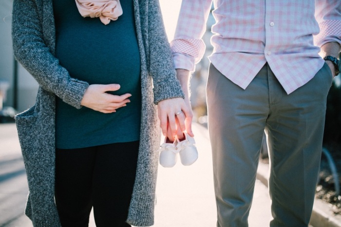 Pregnant couple with baby shoes. 