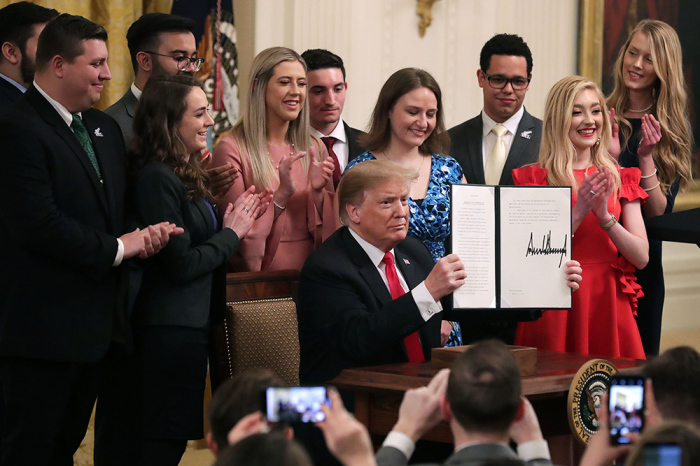 U.S. President Donald Trump holds up an executive order he signed protecting freedom of speech on college campuses during a ceremony in the East Room at the White House in Washington D.C. on March 21, 2019. Surrounded by student who have said their conservative views are suppressed at universities across the country.