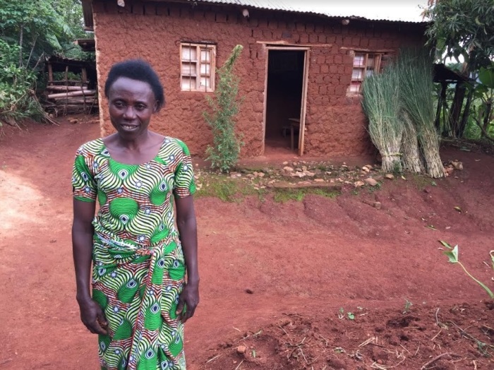 Adissa poses for a photo in front of her house in Rwanda's Western Province in February 2019. By participating in a women's savings association aided by World Vision, she was able to save up 'brick by brick' to build a new home. 