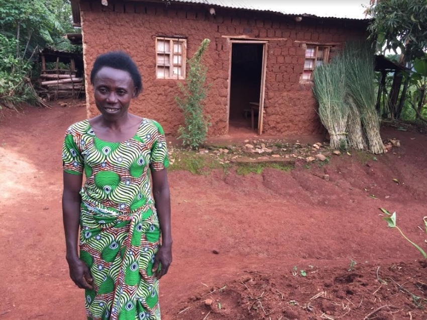 Adissa poses for a photo in front of her house in Rwanda's Western Province in February 2019. By participating in a women's savings association aided by World Vision, she was able to save up 