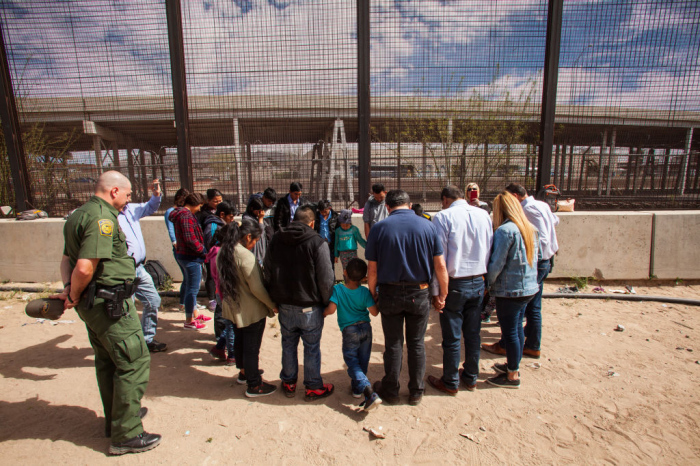 A group of evangelical pastors pray with a group of 22 migrants from Honduras, Guatemala and Salvador underneath the Paso Del Norte Bridge where they are being held for processing in El Paso, Texas, on March 28, 2019. 