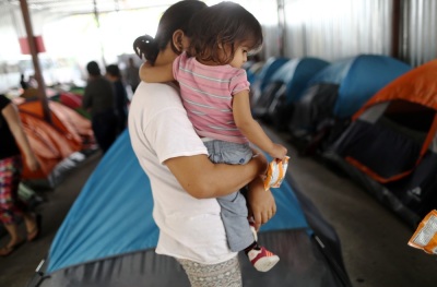 A Honduran mother holds one of her two daughters in the migrant shelter where they are currently living near the U.S.-Mexico border on April 4, 2019 in Tijuana, Mexico. 