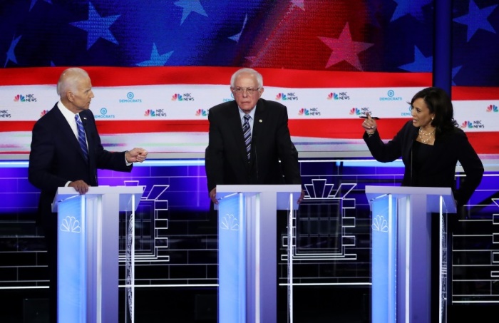 Sen. Kamala Harris (R) (D-CA) and former Vice President Joe Biden (L) speak as Sen. Bernie Sanders (I-VT) looks on during the second night of the first Democratic presidential debate on June 27, 2019 in Miami, Florida. A field of 20 Democratic presidential candidates was split into two groups of 10 for the first debate of the 2020 election, taking place over two nights at Knight Concert Hall of the Adrienne Arsht Center for the Performing Arts of Miami-Dade County, hosted by NBC News, MSNBC, and Telemundo. 