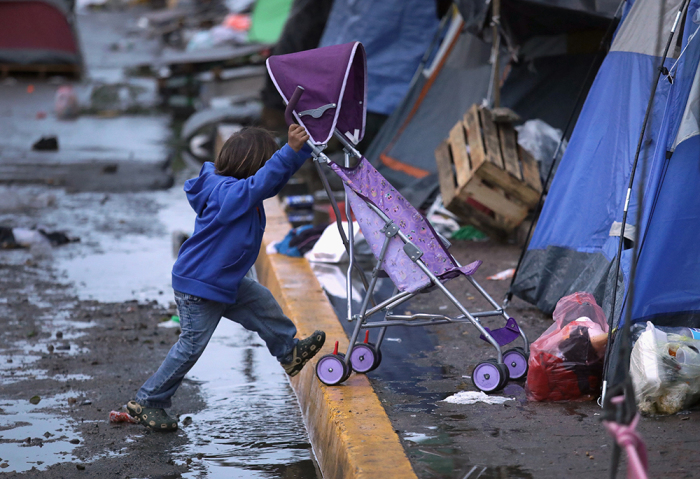 A child pushes a stroller outside a closed temporary migrant shelter on December 6, 2018, in Tijuana, Mexico. After traveling more than six weeks from Central America and arriving to the U.S. border, members of the migrant caravan are increasingly seeing the long odds of crossing successfully into the United States. 