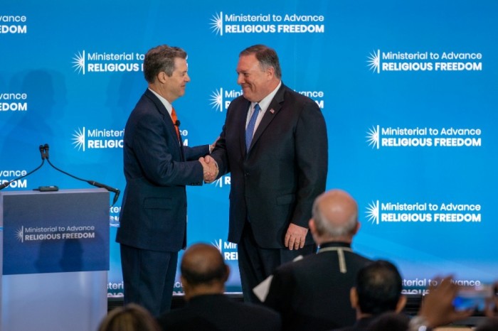 Ambassador-at-large for International Religious Freedom Sam Brownback (L) greets Secretary of State Mike Pompeo (R) before he makes his introductory remarks at the State Department's second Ministerial to Advance Religious Freedom in Washington, D.C. on July 16, 2019. 