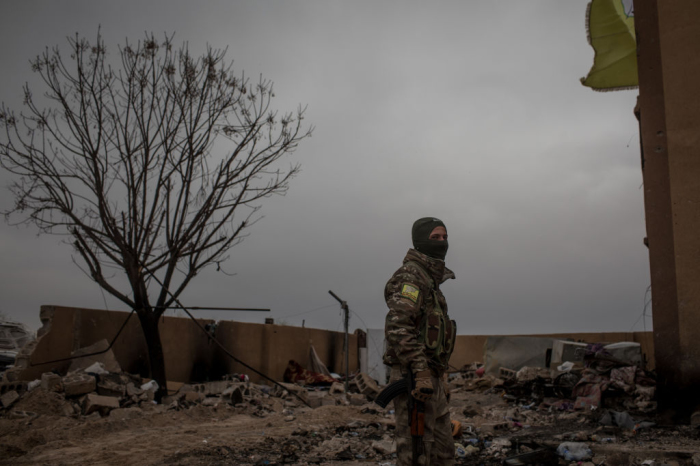 A Syrian Democratic Forces soldier fighterstands in the courtyard of a building at a position in the final ISIL encampment Baghouz, Syria, on March 24, 2019. 