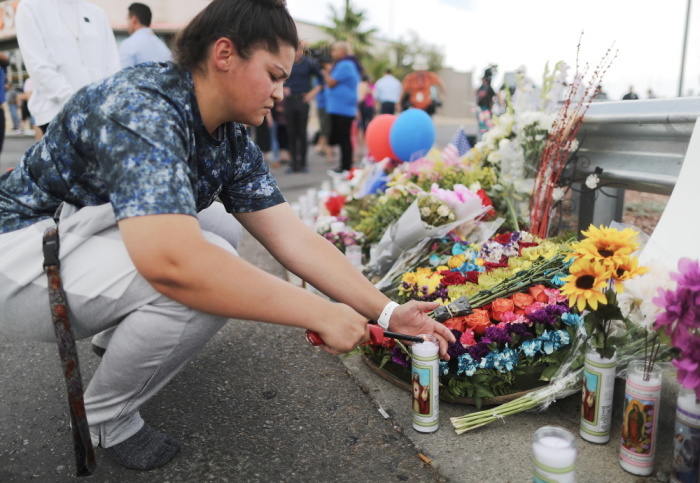 A woman lights a candle at a makeshift memorial outside Walmart, near the scene of a mass shooting which left at least 20 people dead, on August 4, 2019 in El Paso, Texas. A 21-year-old male suspect was taken into custody in the city which sits along the U.S.-Mexico border. At least 26 people were wounded.