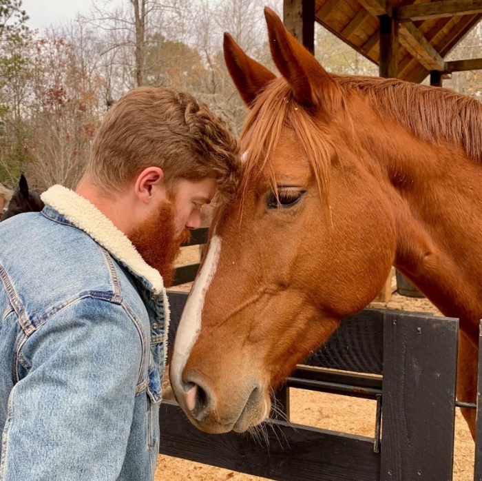 A man and horse share a tender moment.