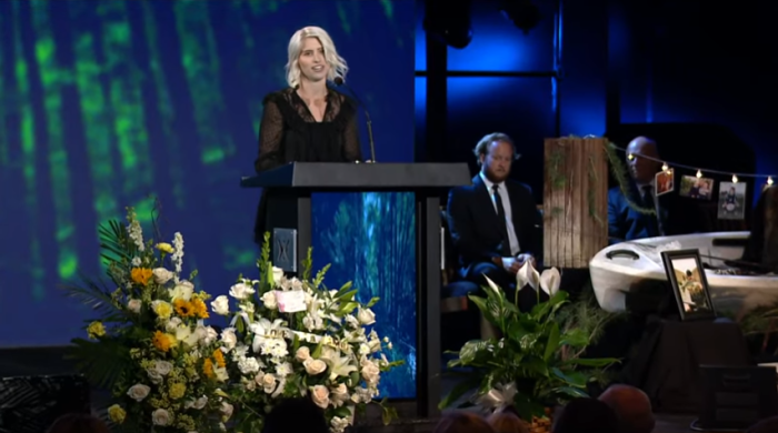 Jarrid Wilson's widow, Juli (podium) speaks at his memorial service at Harvest Christian Fellowship in Riverside, Calif., on Tuesday September 24, 2019. The church's senior pastor, Greg Laurie (L) as well as his youngest son and administrative pastor, Jonathan Laurie, look on. 
