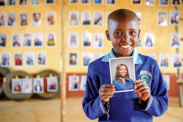 Sponsor child Mary Nzioki from Mwala, Kenya holds up the picture of 35-year-old Olayinka Owolabi, a Chicago lawyer whom she selected to be her sponsor as part of World Vision's Chosen initiative.
