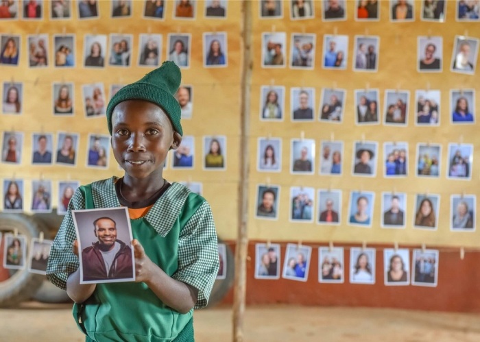 Sponsor child Rosemary Wausi from Mwala, Kenya holds up the picture of Regis Storey, a mental health therapist in Chicago whom she selected to be her sponsor as part of World Vision's Chosen initiative.