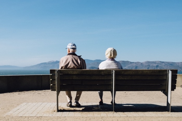 An elderly couple sits on a bench at Lands End Lookout in San Francisco, California. 