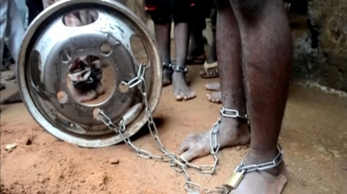 A teenager stands with his feet shackled to a wheel in the Kaduna state of Nigeria. 