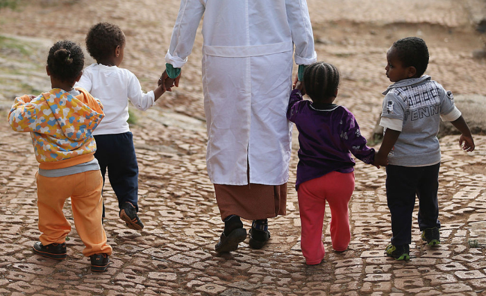 A woman walks with orphans at the AGOHELD orphanage, hospital, training center and school, founded by Abebech Gobena, on March 19, 2013, in Addis Ababa, Ethiopia.