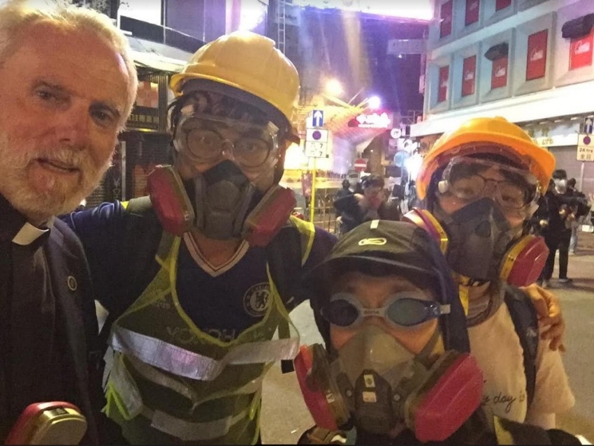 Rev. Bill Devlin (L) and Rev. Patrick Mahoney (center-left) pose for a photo with two Hong Kong pro-democracy protesters during their trip to Hong Kong in November 2019.
