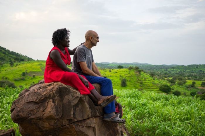 Dr. Tom Catena and his wife, Nasima Mohammed Bashir, sit on a rock in the Nuba Mountains of Sudan. 