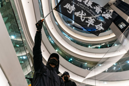 A protester waves a Liberate Hong Kong. The Revolution Of Our Times. at Time Square on December 25, 2019, in Hong Kong, China. Anti-government protesters rally on Christmas day in Hong Kong continue their demands for an independent inquiry into police brutality, the retraction of the word "riot" to describe the rallies, and genuine universal suffrage.