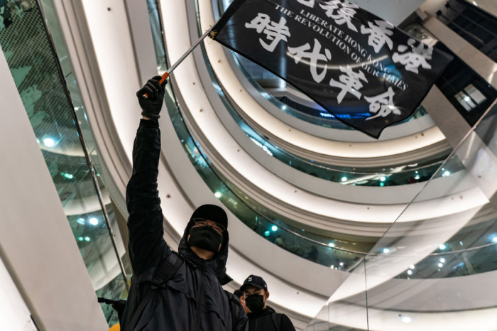A protester waves a Liberate Hong Kong. The Revolution Of Our Times. at Time Square on December 25, 2019, in Hong Kong, China. Anti-government protesters rally on Christmas day in Hong Kong continue their demands for an independent inquiry into police brutality, the retraction of the word 'riot' to describe the rallies, and genuine universal suffrage. 