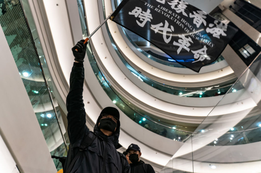 A protester waves a Liberate Hong Kong. The Revolution Of Our Times. at Time Square on December 25, 2019, in Hong Kong, China. Anti-government protesters rally on Christmas day in Hong Kong continue their demands for an independent inquiry into police brutality, the retraction of the word "riot" to describe the rallies, and genuine universal suffrage.