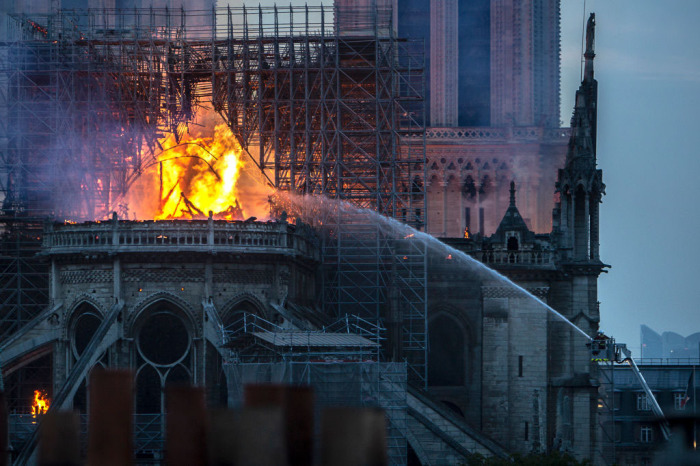Smoke and flames rise from Notre-Dame Cathedral on April 15, 2019, in Paris, France. A fire broke out on Monday afternoon and quickly spread across the building, collapsing the spire. The cause is yet unknown but officials said it was possibly linked to ongoing renovation work. 