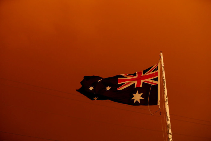 The Australia Flag flies under red skies from the fires on Jan. 4, 2020, in Bruthen, Australia. 