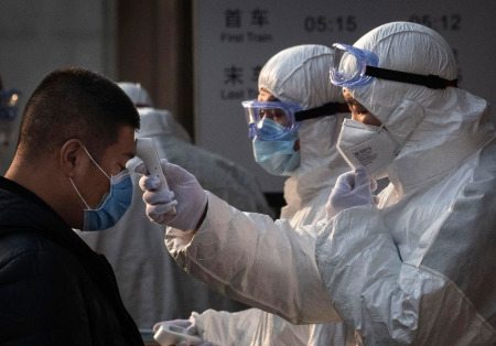 A Chinese health worker checks the temperature of a woman entering a subway station during the Chinese New Year and Spring Festival on January 25, 2020, in Beijing, China.