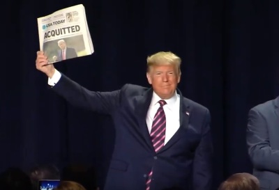 President Donald Trump holds up a newspaper announcing his acquittal at the National Prayer Breakfast in Washington, D.C. on Thursday, Feb. 6, 2020.