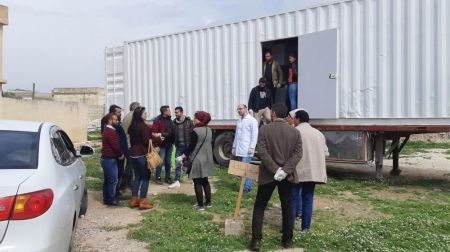 People stand outside of a "hospitainer" mobile medical clinic in Syria.