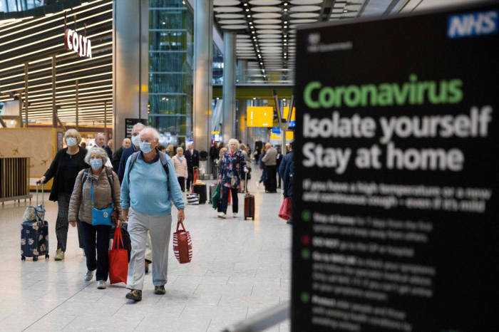 Travellers who had been aboard the Braemar cruise ship, operated by Fred Olsen Cruise Lines, and wearing face masks as a precautionary measure against covid-19, react as they arrive at Heathrow Airport in London on March 19, 2020.