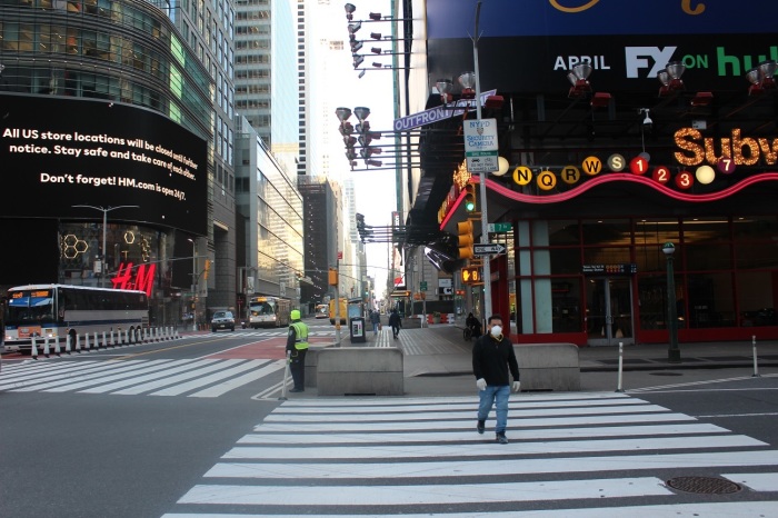 A man crosses the mostly deserted 7 Avenue in Times Square New York City during the coronavirus outbreak.