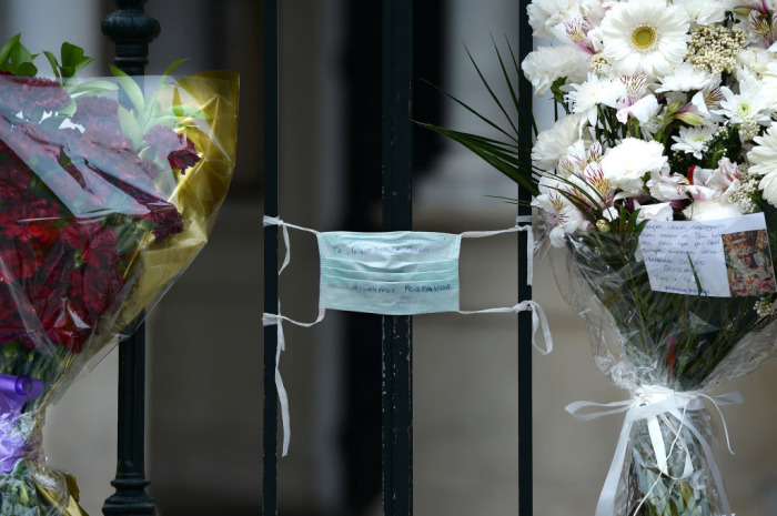 A face mask with the text 'You, the one who can do anything, help us, please' is tied to the fence of La Macarena church on April 9, 2020, in Seville, Spain, adorned with flowers left by the faithful after Easter processions were cancelled during a national lockdown to prevent the spread of the COVID-16 disease. 