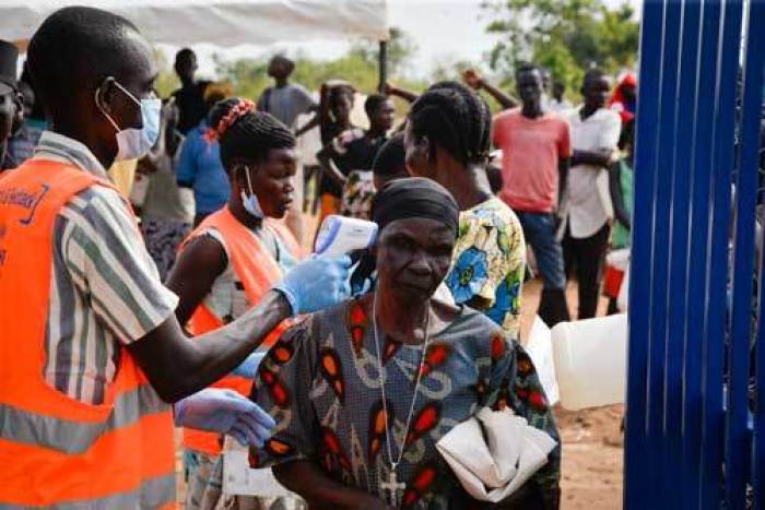 An old woman in Bidi Bidi refugee camp in Uganda, taking the temperature check in before accessing the food distribution point. A World Vision/WFP volunteer checks everyone’s temperature. Anyone with an elevated temperature is ushered into a separate tent and monitored for some time.