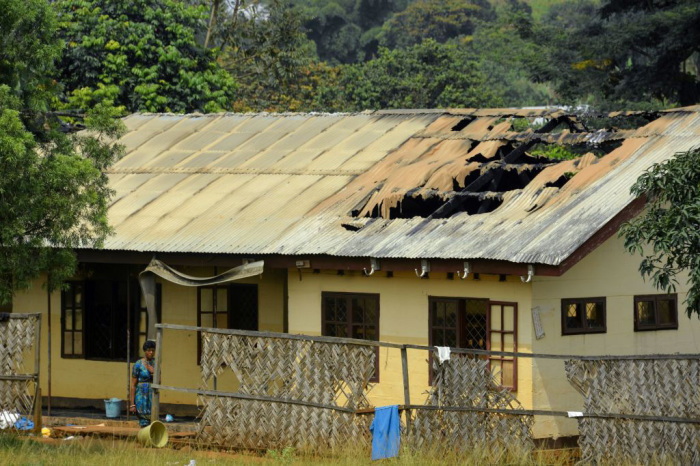 A woman stands outside the damaged roof of a school's dormitory, after it was set to fire overnight in Bafut, on November 15, 2017, in the northwest English-speaking region of Cameroon. 