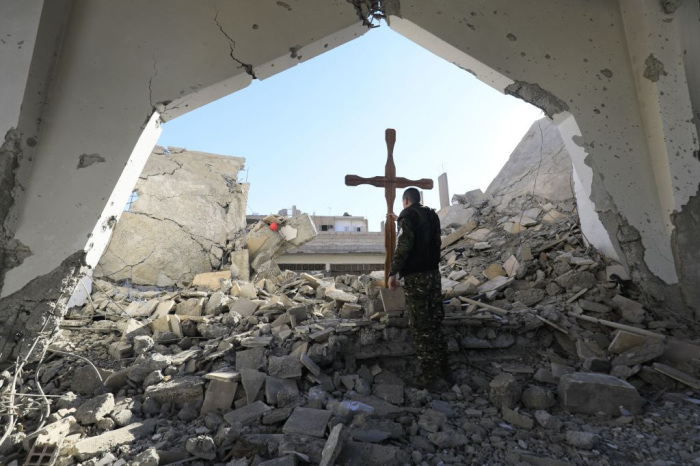 A member of the Syrian Arab-Kurdish forces places a cross in the rubble ahead of a Christmas celebration at the heavily-damaged Armenian Catholic Church of the Martyrs in the city centre of the eastern Syrian city of Raqa on December 26, 2017, following a mine clarence operation at the site a few days earlier. A U.S.-backed offensive ousted the Islamic State group from Raqa in October but the city has been left ravaged by fighting.