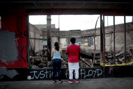People look at the charred wreckage of a building destroyed during last week's rioting sparked by the death of George Floyd on Memorial Day in Minneapolis, Minnesota, on June 2, 2020.