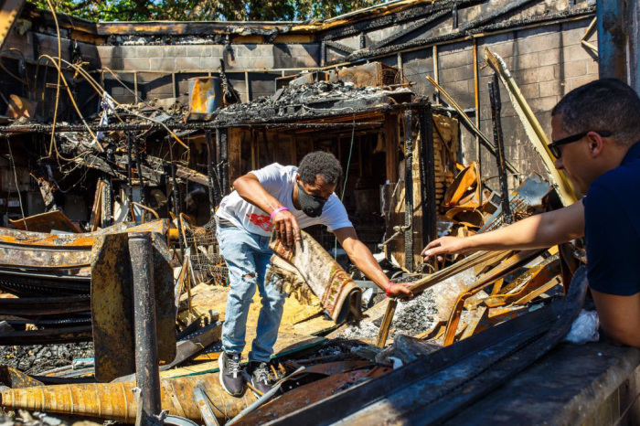 An employee hands the seccade (prayer-rug) to Moroccan Gas station owner Anis Ayani, 37, from the charred wreckage of a Gas station destroyed during last week's rioting sparked by the death of George Floyd on Memorial Day in Minneapolis, Minnesota, June 3, 2020.
