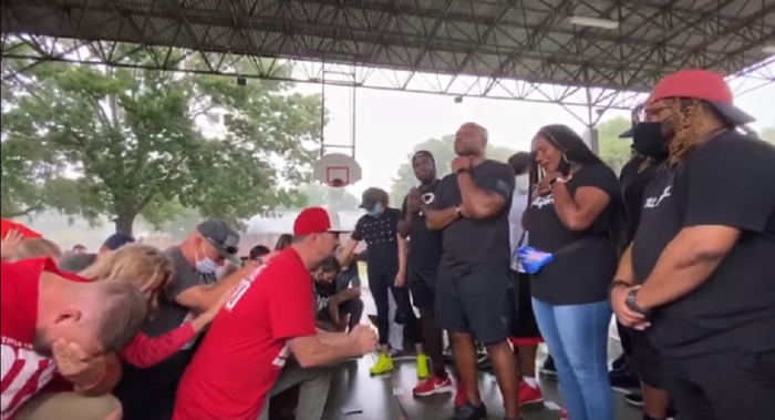 Christian rapper Bobby “Tre9” Herring (kneeling in red and white cap) and other white Christians repent of racism before black Christians.