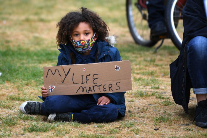 A young girl prepares for the Take The Knee demonstration in solidarity with Black Lives Matter in Windrush Square, Brixton, southwest London on June 10, 2020. 