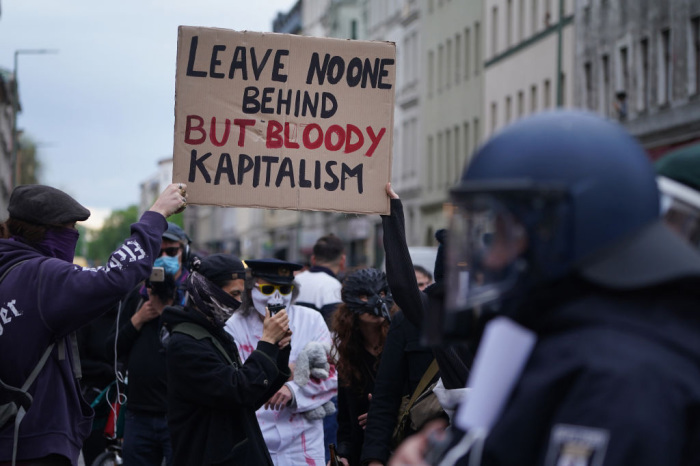 Activists protest against capitalism as riot police stand nearby during scattered left-wing protests in Kreuzberg district on May Day during the novel coronavirus crisis on May 1, 2020, in Berlin, Germany. 