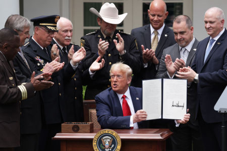 Surrounded by members of law enforcement, U.S. President Donald Trump holds up an executive order he signed on 'Safe Policing for Safe Communities' during an event in the Rose Garden at the White House on June 16, 2020, in Washington, DC.