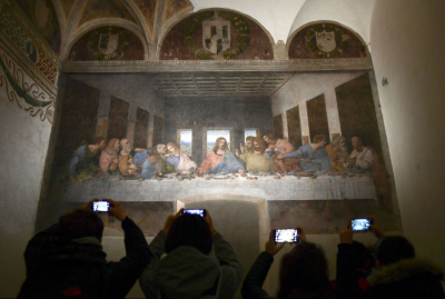 Visitors with their mobile phone take photos of 'The Last Supper' (Il Cenacolo or L'Ultima Cena), Italian artist Leonardo da Vinci's late 15th-century mural painting housed by the refectory of the Convent of Santa Maria delle Grazie in Milan, on May 8, 2019. - The mural has been undergoing ongoing restoration for years by a small team of experts, led by renowned Italian art restorer Pinin Brambilla. 2019 marks the 500th anniversary of the death of the artist and inventor.