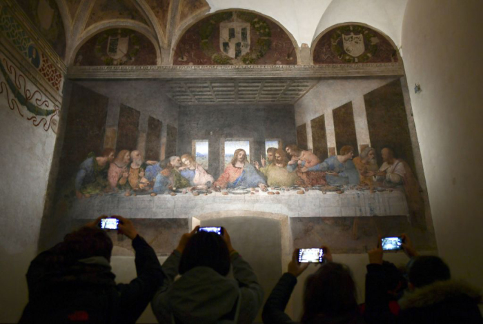 Visitors with their mobile phone take photos of 'The Last Supper' (Il Cenacolo or L'Ultima Cena), Italian artist Leonardo da Vinci's late 15th-century mural painting housed by the refectory of the Convent of Santa Maria delle Grazie in Milan, on May 8, 2019. - The mural has been undergoing ongoing restoration for years by a small team of experts, led by renowned Italian art restorer Pinin Brambilla. 2019 marks the 500th anniversary of the death of the artist and inventor.