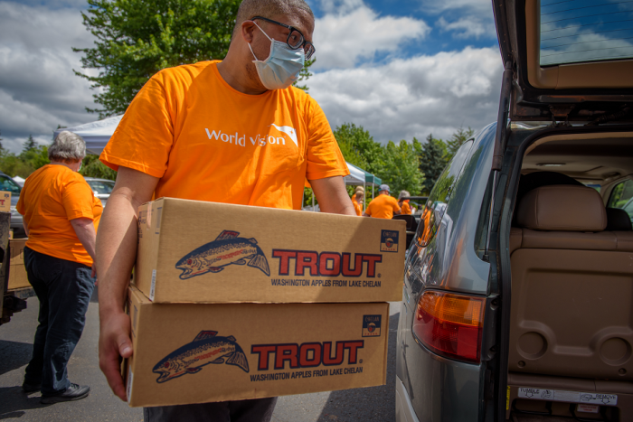 A World Vision volunteer loading a food box into a recipient's car. World Vision's latest partnership is with Lakewood Church, serving the Houston area.