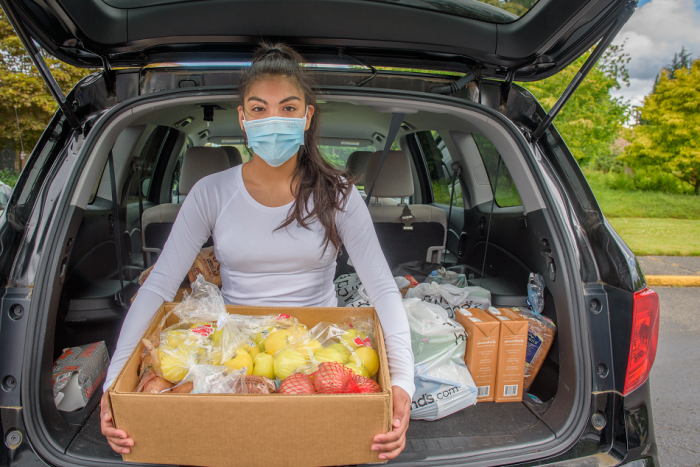 A woman holds a food box, part of the Fresh Food Box Program. Fresh food is provided to those in need during the COVID-19 pandemic, 2020.