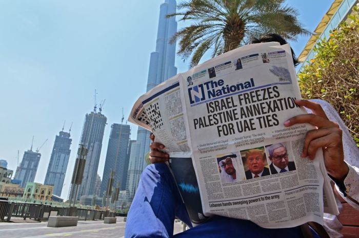 A man reads a copy of UAE-based The National newspaper near the Burj Khalifa, the tallest structure and building in the world since 2009, in the gulf emirate of Dubai on August 14, 2020. 