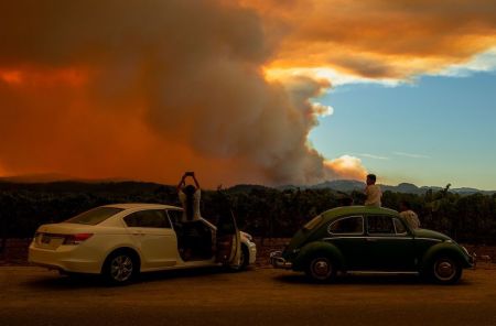 People watch the Walbridge fire, part of the larger LNU Lightning Complex fire, from a vineyard in Healdsburg, California on August 20, 2020. A series of massive fires in northern and central California forced more evacuations as they quickly spread August 20, darkening the skies and dangerously affecting air quality.